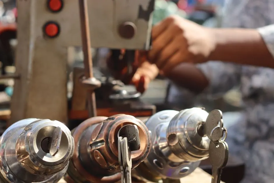 Close-up image of locksmith tools and hands working with a key machine outdoors.